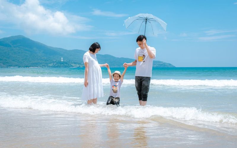 Happy family enjoying a sunny day at Da Nang Beach, Vietnam, playing in the waves.